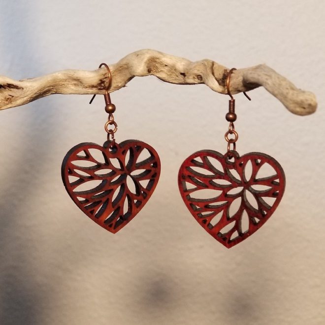 Heart earrings hanging on driftwood.