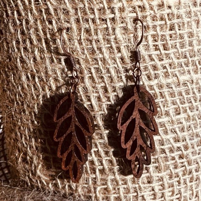 Cascading leaf walnut earrings hanging on a burlap backdrop.